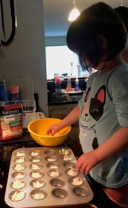 My daughter putting the mix from the bowl into the mini muffin tin