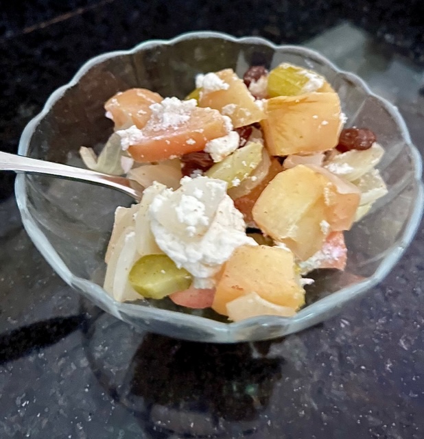 Roast Apple, Onion, Celery with Goat Cheese and Raisins in a bowl with spoon on a black counter